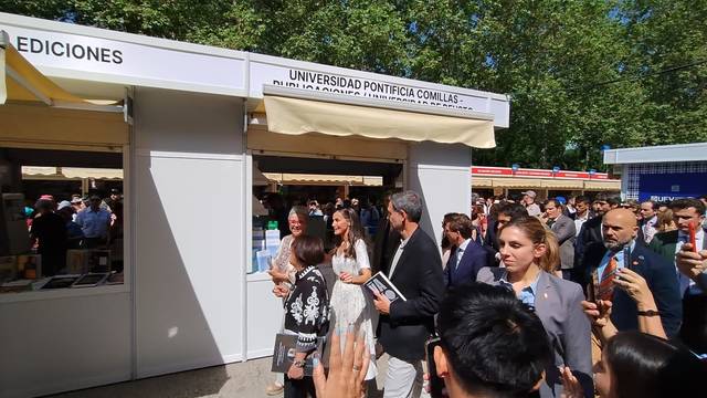 Una multitud de personas en un evento en la Universidad Pontificia Comillas, con un estand visible de la misma.