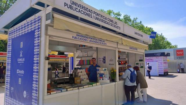 Un stand de la Universidad Pontificia Comillas y la Universidad de Deusto con libros y publicaciones en exhibición.