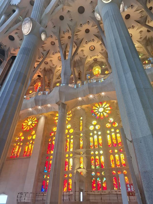 Vista interior de la Sagrada Familia con columnas y vitrales coloridos.
