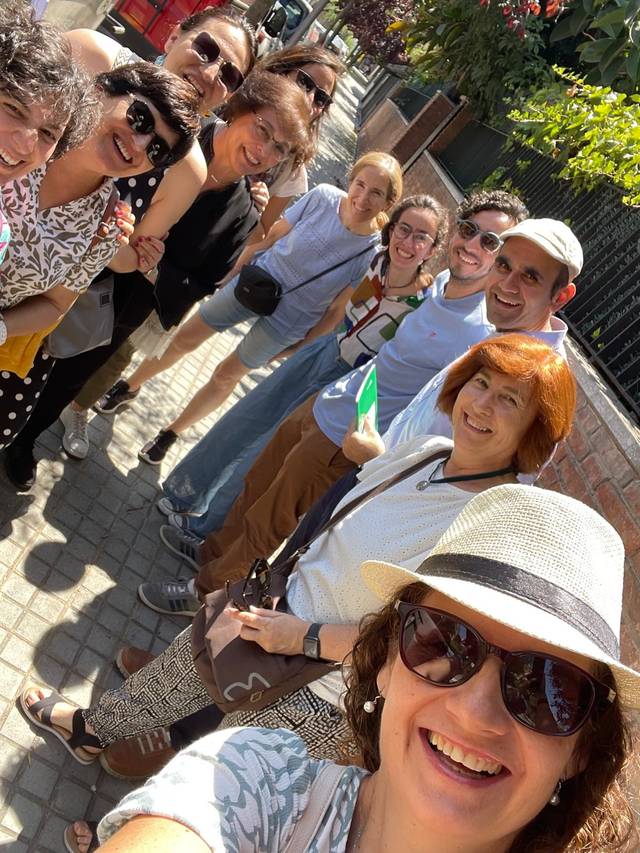 Un grupo de personas sonrientes se agrupan en la calle para tomar una foto juntos.
