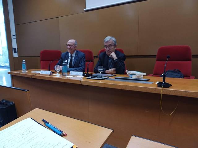 Dos hombres sentados en un aula durante una presentación.