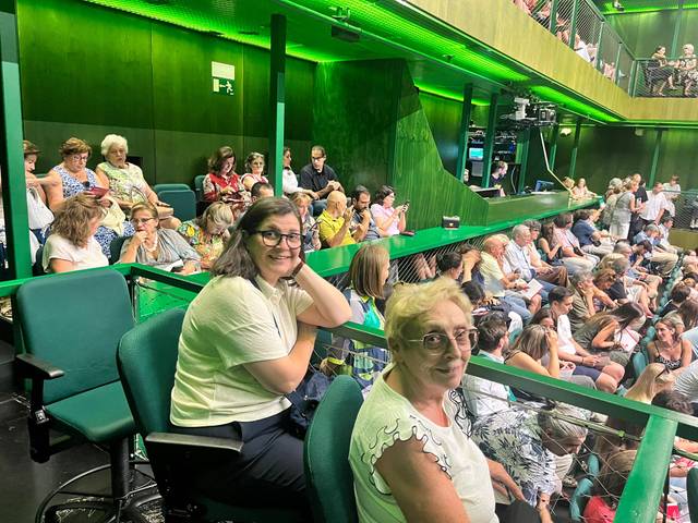 Un grupo de personas sentadas en un auditorio con iluminación verde.