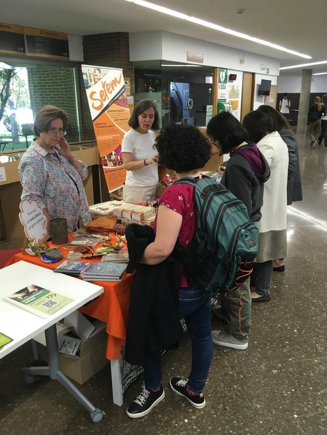 Una feria donde varias personas están interactuando y mirando productos en un stand.