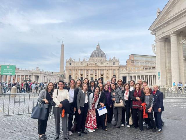 Un grupo de personas posando frente a la Basílica de San Pedro en el Vaticano.