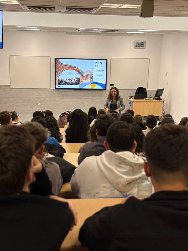 Una ponente habla frente a un grupo de estudiantes en un aula moderna.
