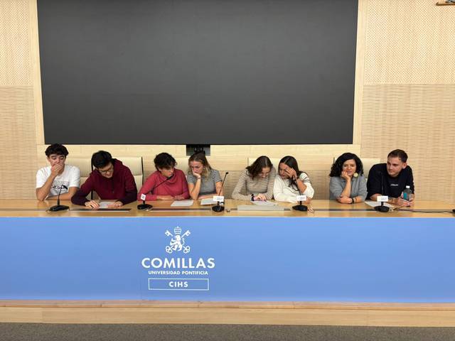 Un grupo de estudiantes sentados en una mesa durante un evento en la Universidad Pontificia Comillas.