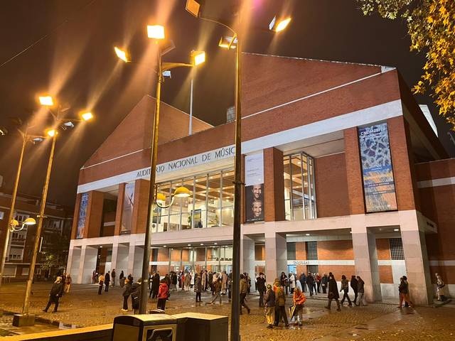 Edificio del Museo Nacional de Música iluminado por la noche con un grupo de personas en la entrada.