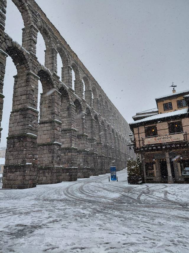 Un acueducto monumental se erige bajo la nevada en un paisaje invernal.