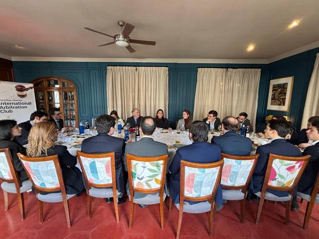 Un grupo de personas discute en una reunión formal alrededor de una mesa.