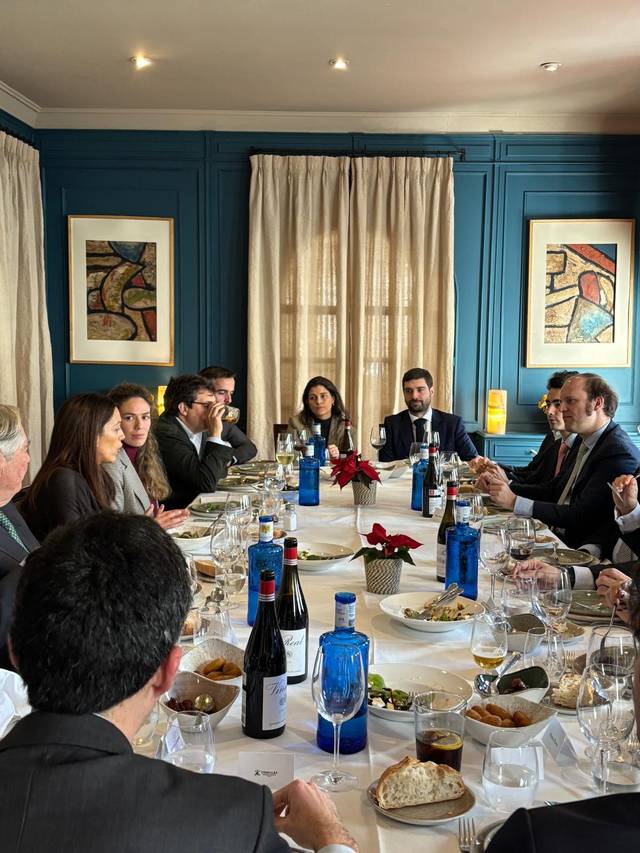 Una reunión de varias personas alrededor de una mesa en un ambiente elegante.
