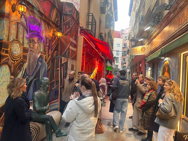 Un grupo de personas observan una escultura en una calle adornada con murales coloridos.