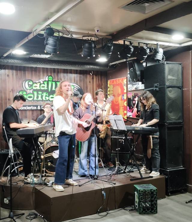 Una banda toca en vivo en un escenario con varios instrumentos musicales.