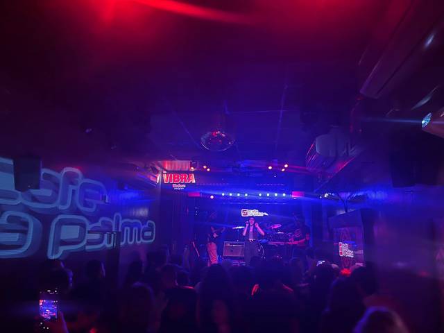 Una actuación en un bar con luces oscuras y un ambiente animado.