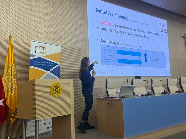 Una presentadora explica la relación entre el estado de ánimo y la alimentación en una conferencia.