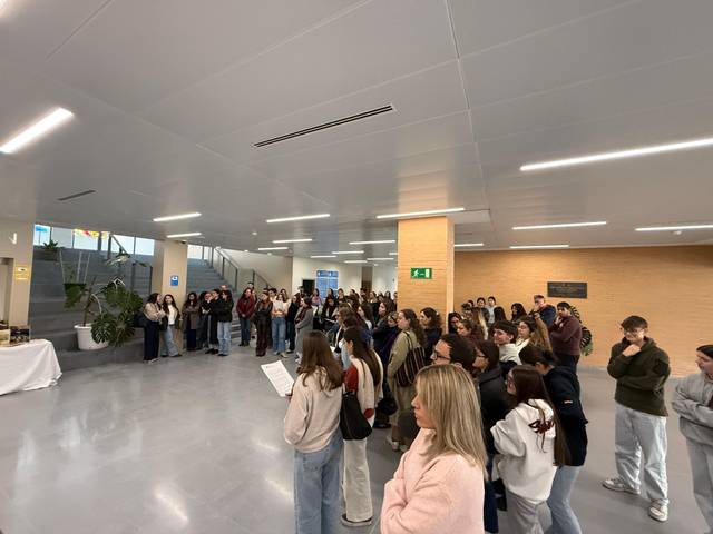 Un grupo numeroso de personas se encuentra reunido en un espacio interior amplio, formando un público atento.
