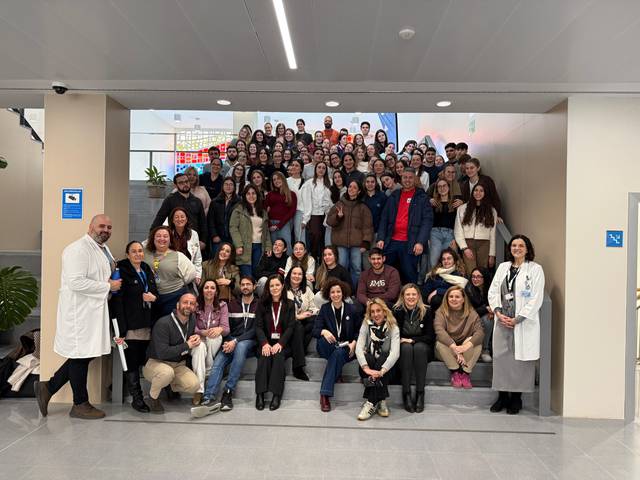 Un grupo grande de personas posando en una escalera en un entorno interior moderno.