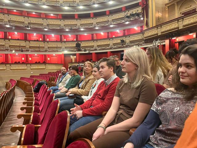 Un grupo de personas sentadas en un teatro, preparando para una función.