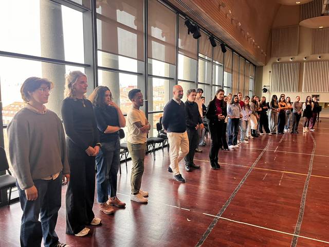 Un grupo de personas en fila en un espacio interior con grandes ventanales.