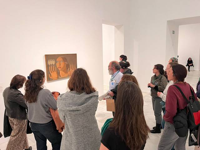 Un grupo de personas observa una pintura en una galería de arte moderna.