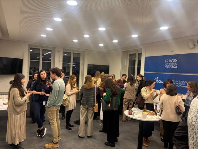 Un grupo de personas conversando y socializando en un evento interior.