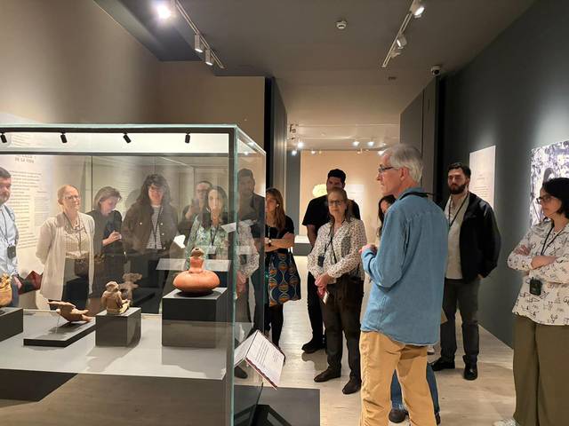 Un grupo de personas escucha a un guía frente a una exposición de artefactos en un museo.