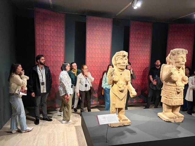Un grupo de personas observa estatuas de piedra en una exposición cultural.
