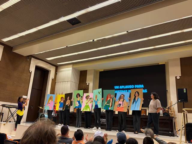 Un grupo de personas sostiene retratos en una presentación pública.