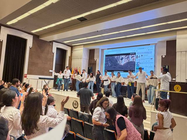 Un grupo de personas baila y celebra en un auditorio durante un evento.