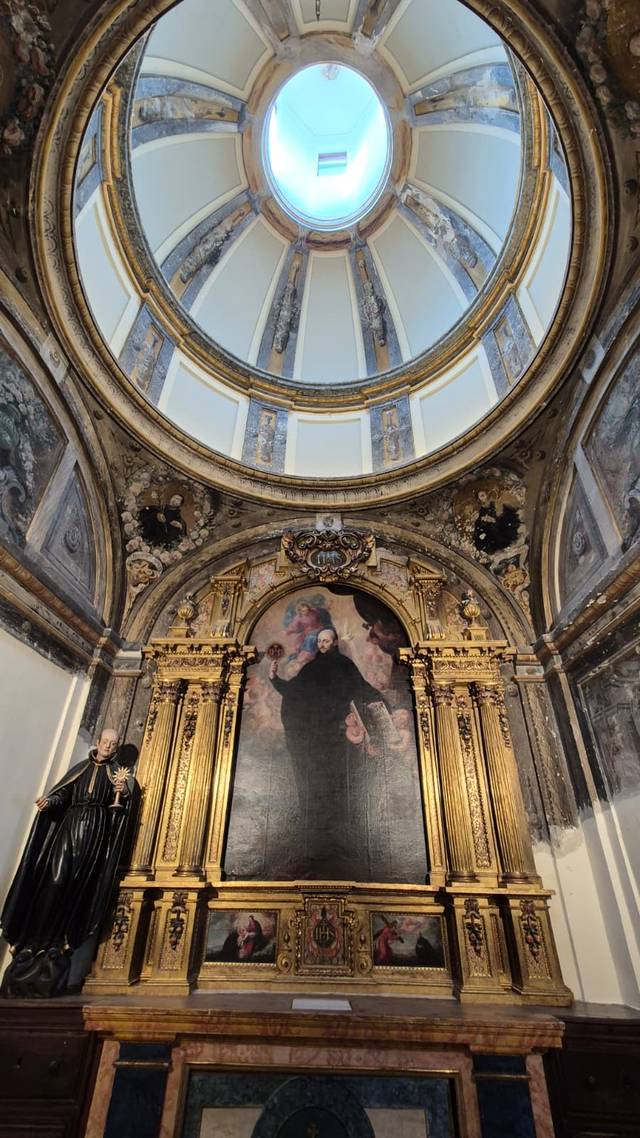 Imagen del interior de una iglesia con un altar decorado y una cúpula iluminada.