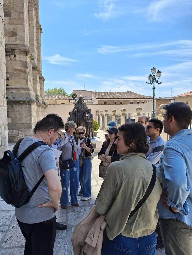 Un grupo de personas escucha atentamente a un guía en una plaza histórica.