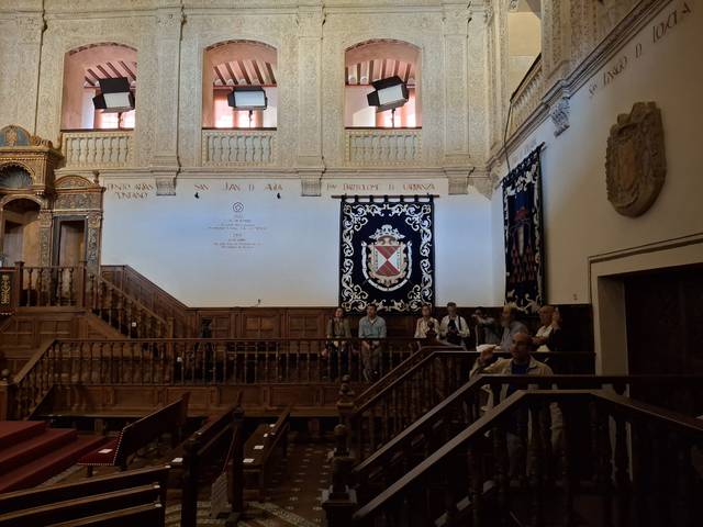Una vista del interior de un edificio histórico con balcones de madera y un gran estandarte en la pared.