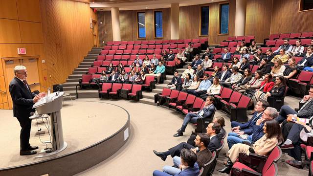 Un orador se presenta ante un público en un auditorio lleno de gente.