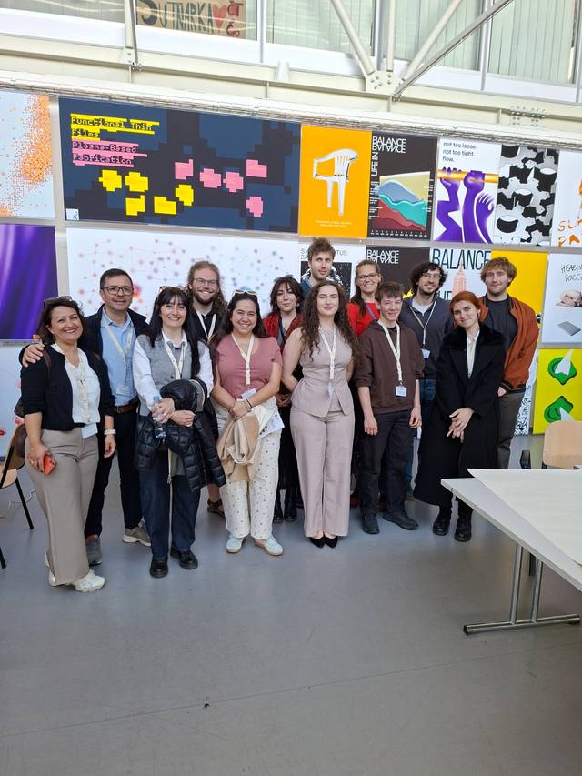 Grupo de personas posando en un evento artístico frente a fondos coloridos.