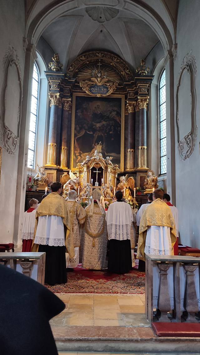 Una ceremonia religiosa con sacerdotes de espaldas en un altar decorado.
