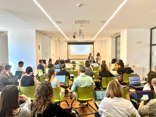 Una sala de conferencias con asistentes sentados frente a una presentación en pantalla.