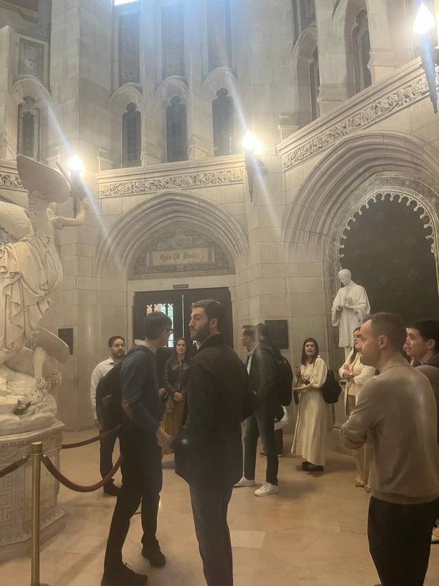 Un grupo de personas observa esculturas en un elegante vestíbulo de un edificio antiguo.