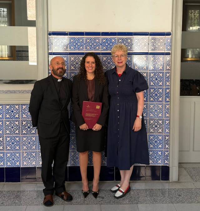La imagen muestra a tres personas posando frente a un fondo de azulejos, celebrando un logro académico.