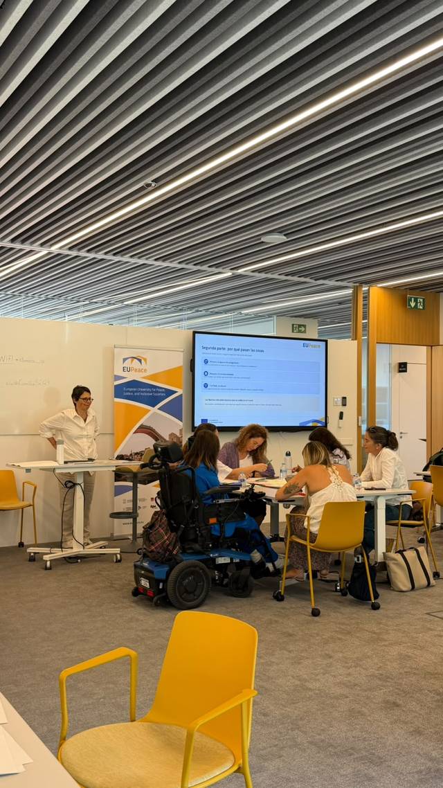 Un grupo de personas en un aula moderna trabajando en equipo mientras una persona dirige la sesión.