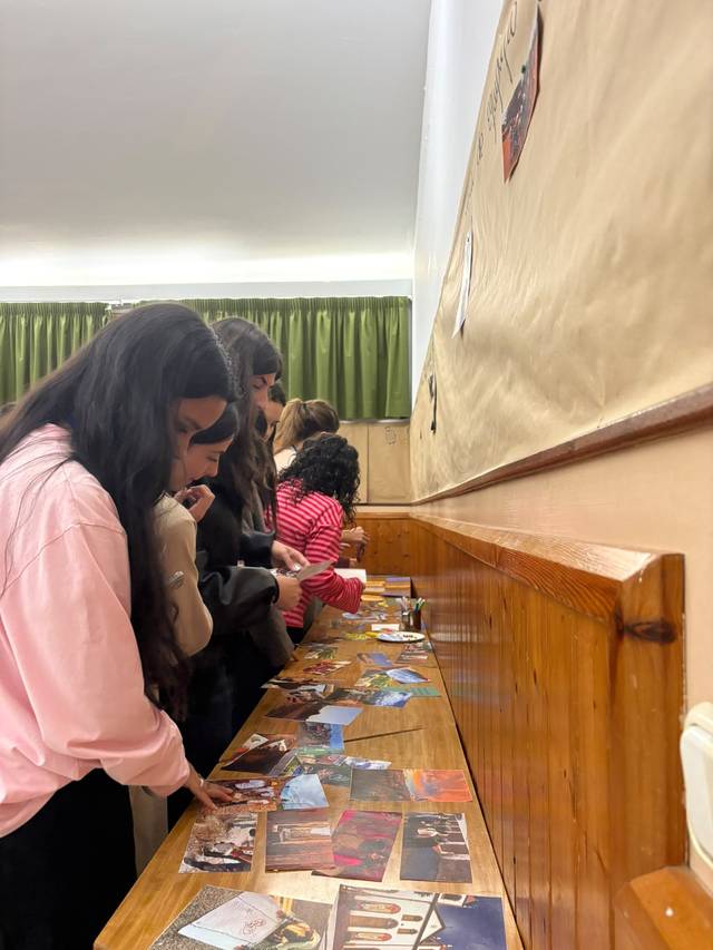 Un grupo de personas observa y manipula una serie de fotografías sobre una mesa.