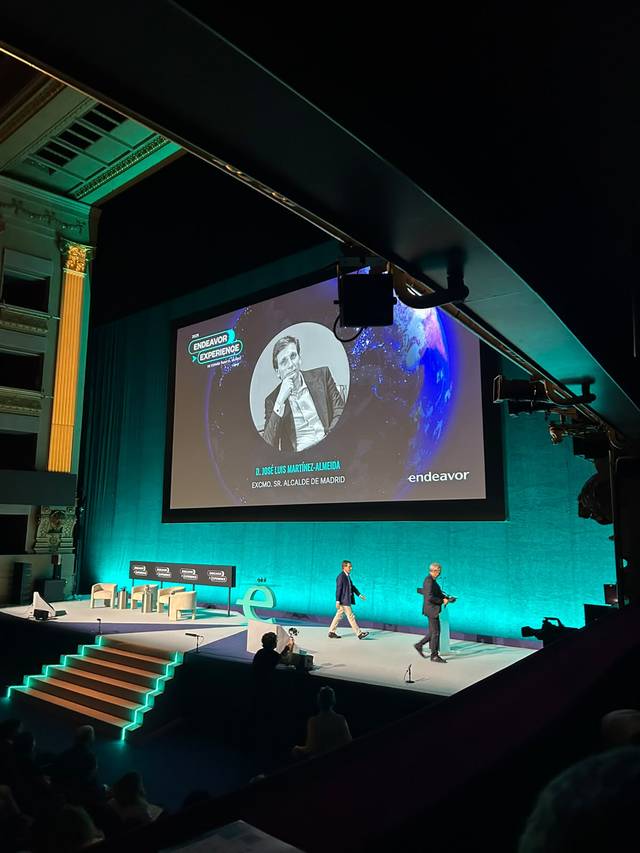 Una presentación en un evento con un escenario iluminado y un fondo que muestra una imagen del planeta.