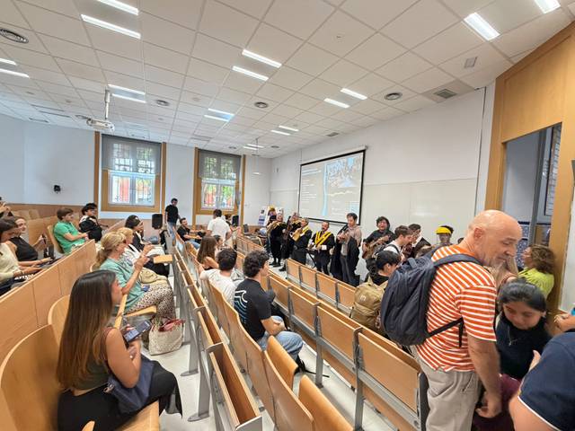 Un grupo de personas se encuentra en una sala con asientos en un ambiente académico.