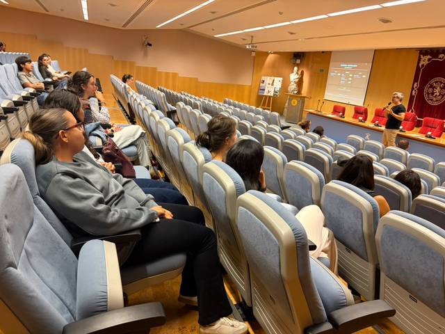 Una sala de conferencias con un grupo de personas escuchando atentamente a un presentador.