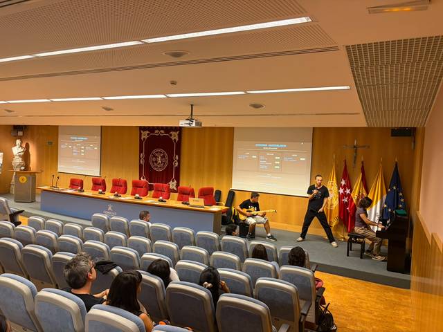 Una sala de conferencias con un grupo de personas interactuando y un pianista en el escenario.