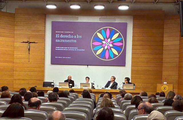 Un panel de discusión sobre el derecho a los sacramentos en un auditorio con público presente.