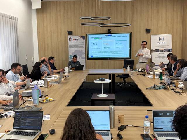 Reunión de trabajo con varios participantes discutiendo datos presentados en una pantalla.