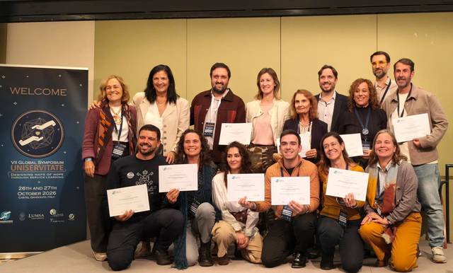 Un grupo de personas sonrientes sosteniendo certificados en un evento, rodeados de un ambiente de celebración.