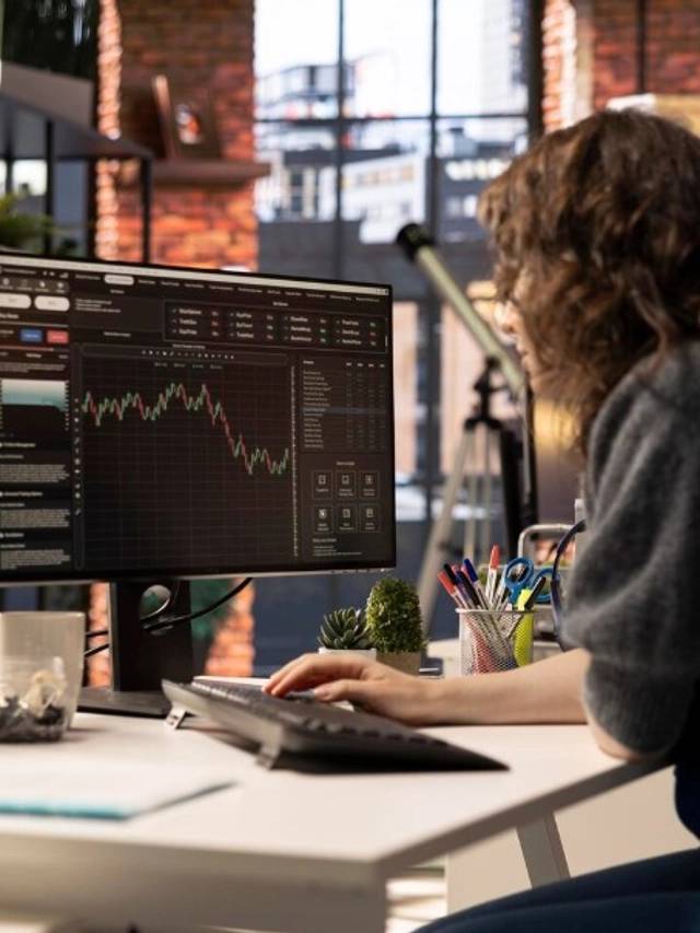 Una persona trabajando en un ordenador con gráficos financieros en pantalla.