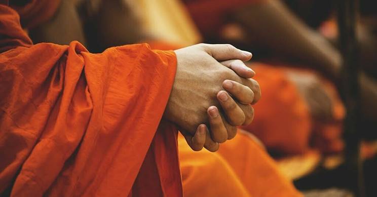 Las manos de un monje en un entorno de meditación.