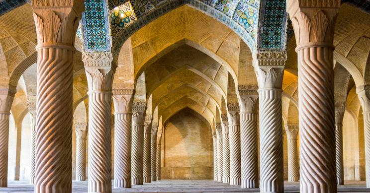 Un interior de columnas con arcos en un edificio monumental que destaca por su arquitectura islámica.