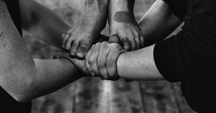 Cinco manos y pies están entrelazados en un gesto de unidad y conexión.